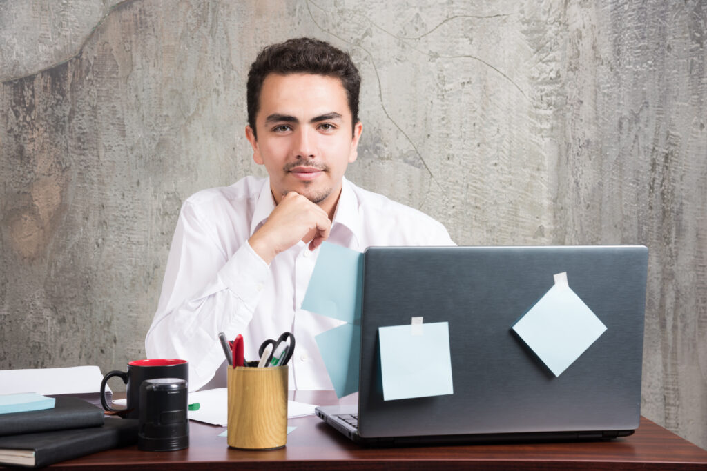 young businessman posing happily at the office desk
